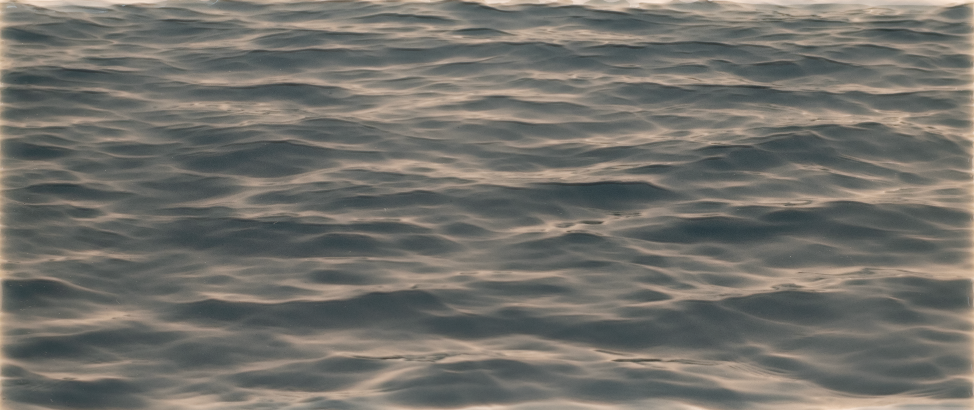 reflecting light, representing the calming aesthetic of the 'Pebble Shore Style' tile mural for shower walls by Living Walls Tile.