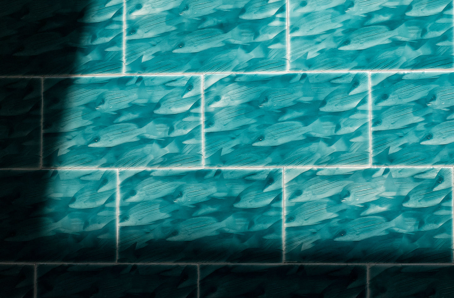 Coastal-themed tile featuring a pattern of swimming fish in shades of teal, ideal for enhancing bathroom decor with a tropical aesthetic.
