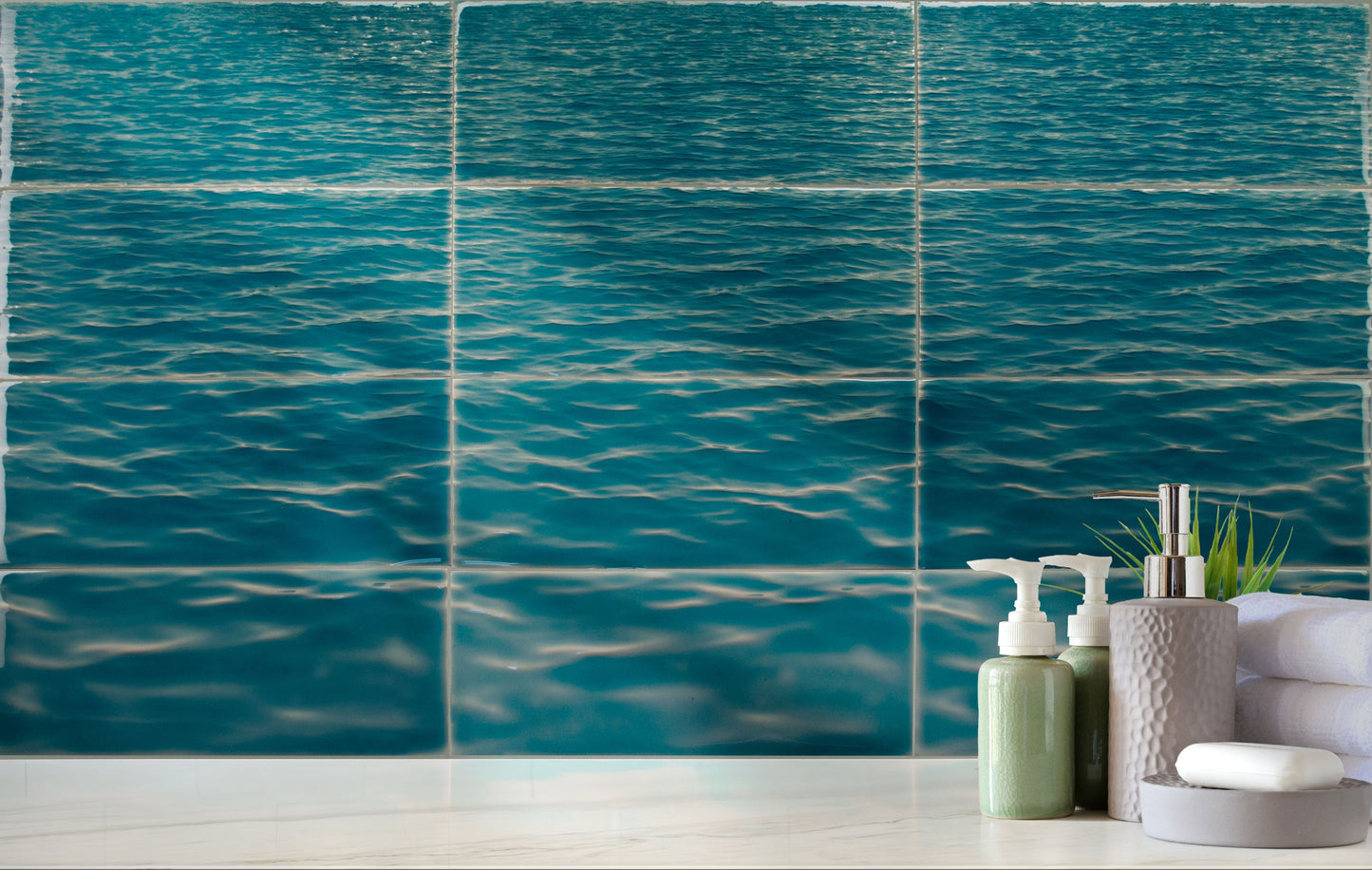 Beach-themed bathroom tile mural featuring calming ocean waves in shades of blue, with decorative toiletries and towels in a coastal decor setting.