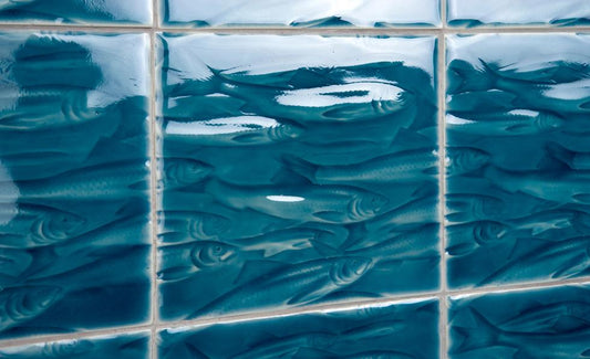 Textured blue tiles featuring a biophilic design of swimming fish, enhancing luxury bathroom aesthetics at Living Walls Tile.