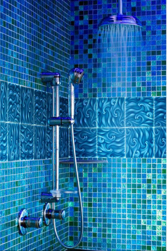 Japanese bathroom featuring wave-patterned blue tiles, chrome shower fixtures, and a vibrant mosaic wall, highlighting artistic inspiration for home decor.